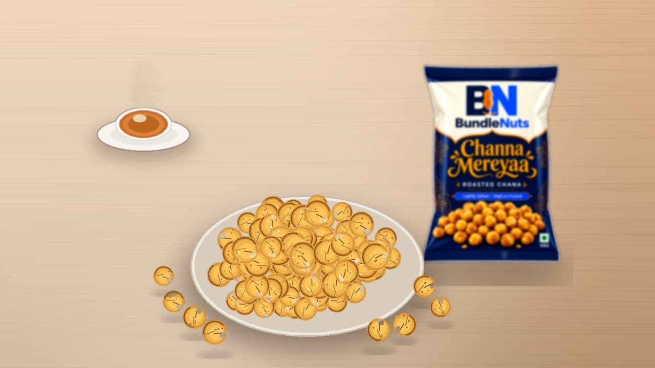 Golden dry-roasted chana in a white serving bowl beside hot cutting chai with a BundleNuts Roasted Chana pack softly in the background.